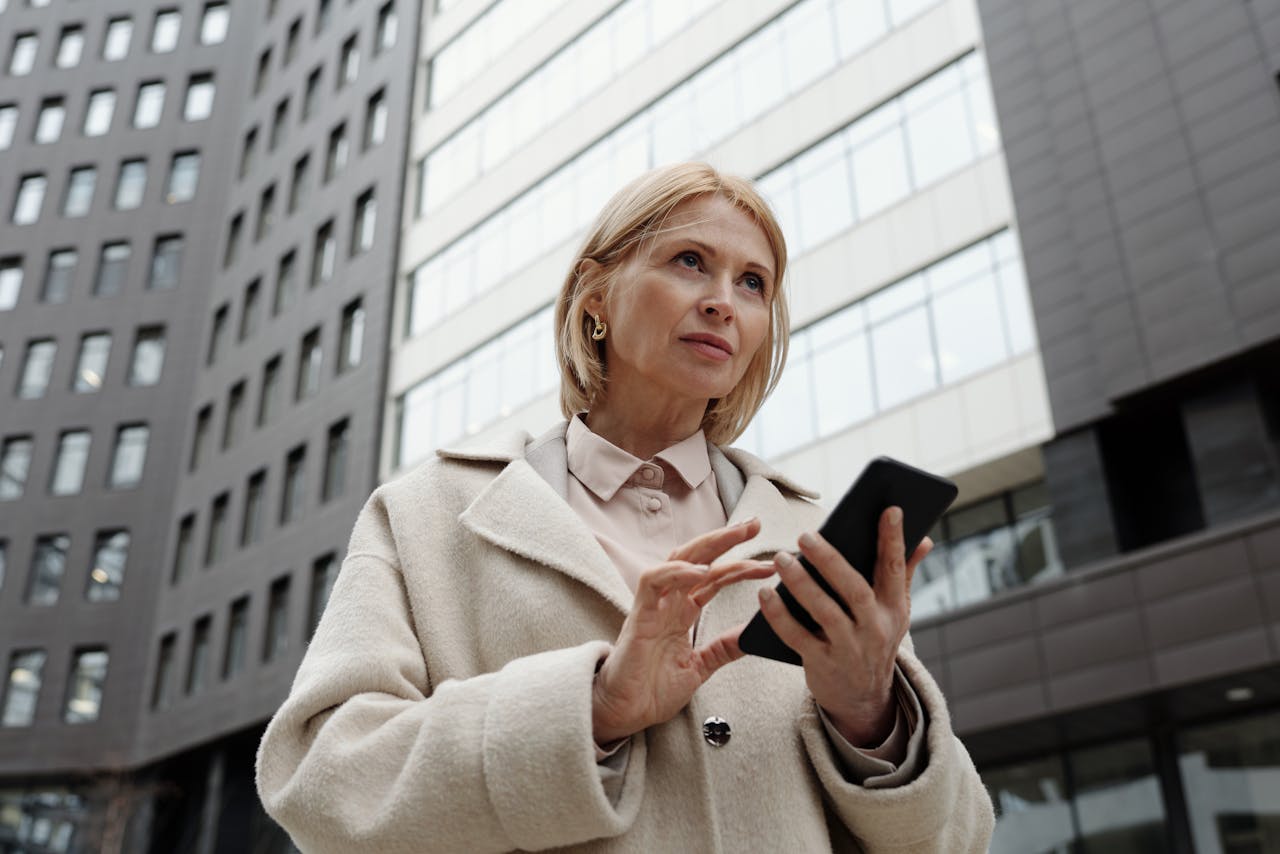 mujer-con-dispositivo-movil-delante-de-oficinas-con-iot-en-empresas